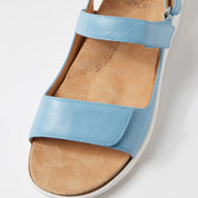 Blue sandal with tan insole on a light gray background
