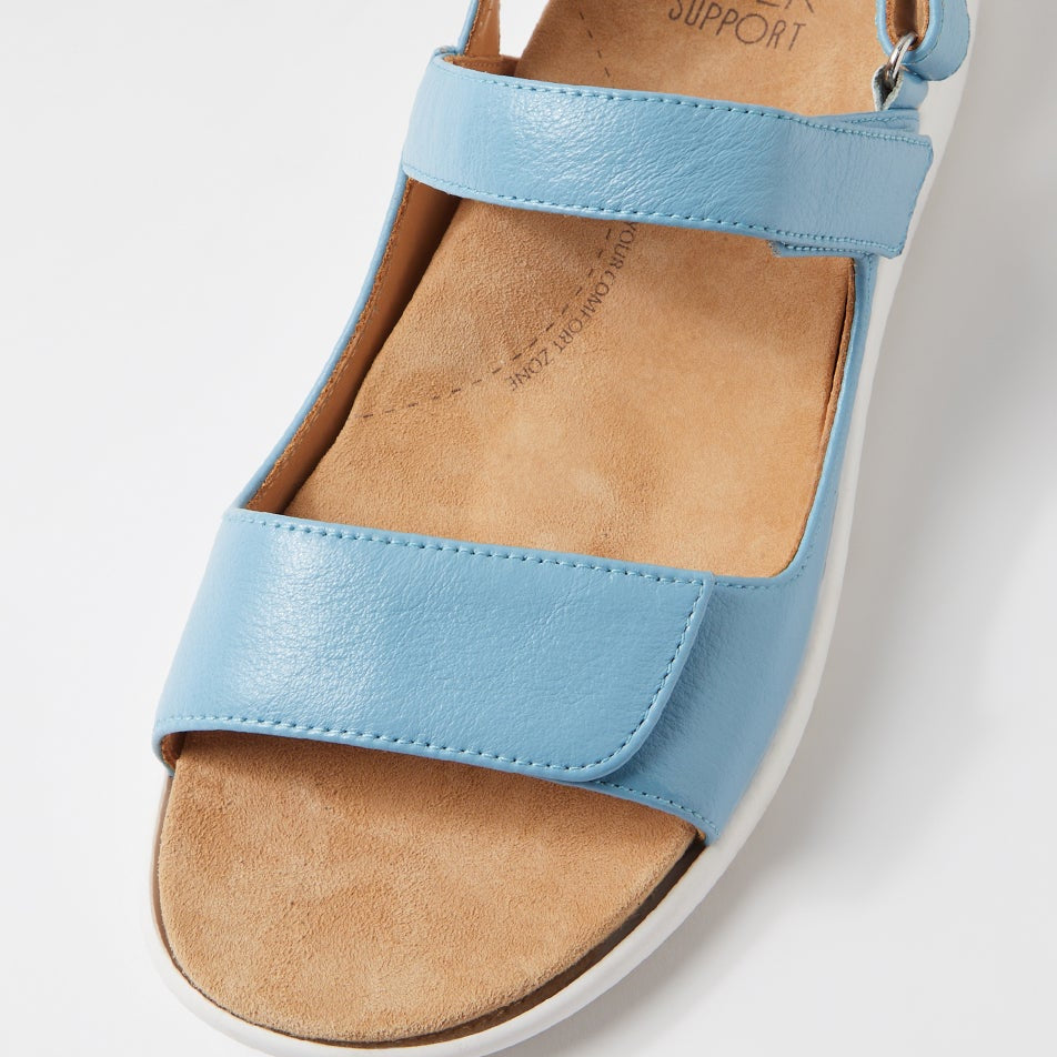 Blue sandal with tan insole on a light gray background