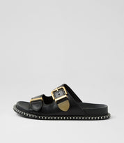 Ziera Iyami sandal in black leather with adjustable straps, brass accents, and supportive low-profile sole on a white background